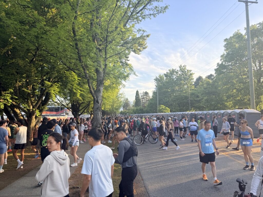 Long portable toilet lines at the BMO Vancouver Half Marathon start area near Queen Elizabeth Park
